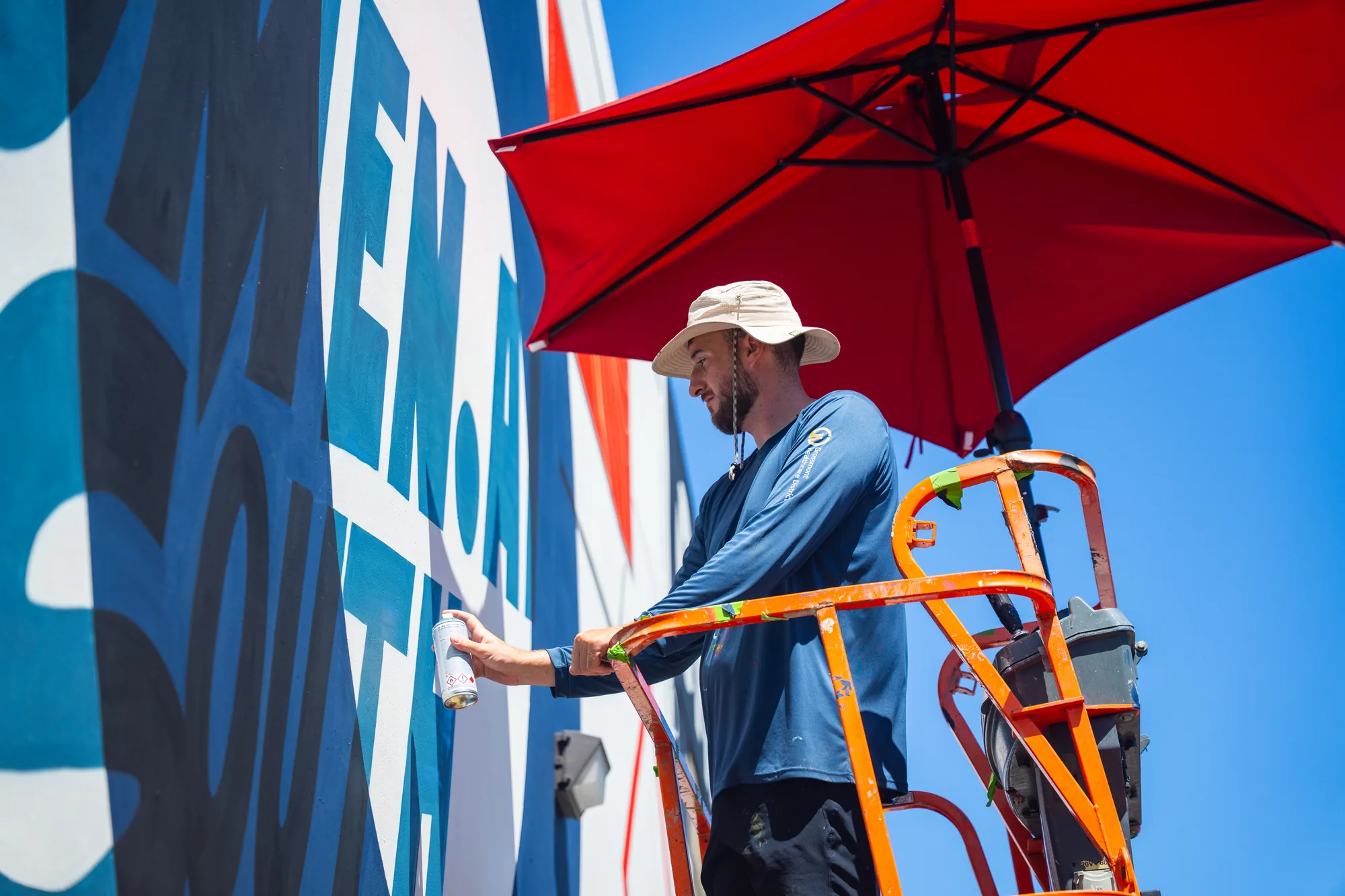 Mural being painted from a boom lift
